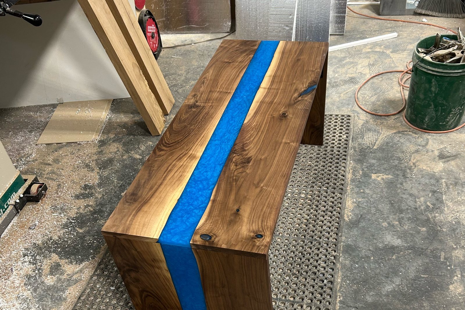 Walnut and blue epoxy waterfall bench on the floor of the Billings shop